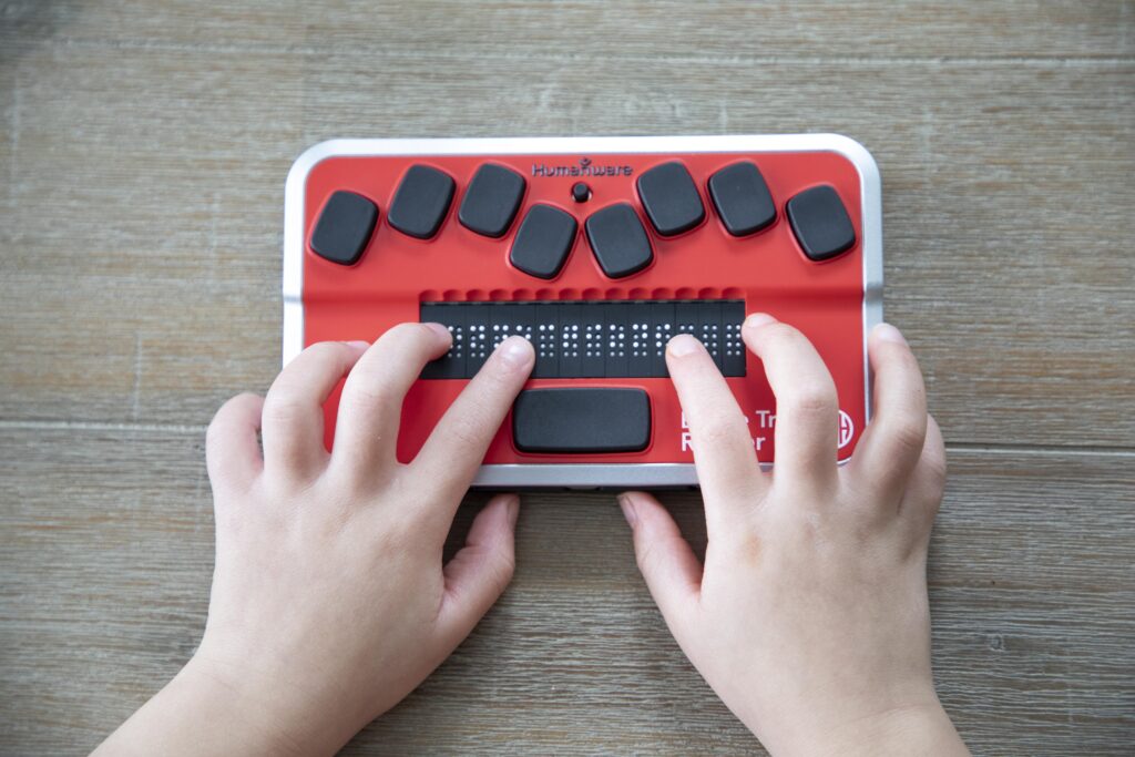 top view of a child's hands on a braille display